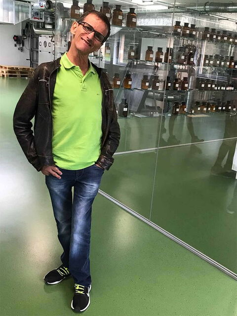 Foto: Andi mit maigrünem T-Shirt und in dunkler Lederjacke vor einem Ladengeschäft.