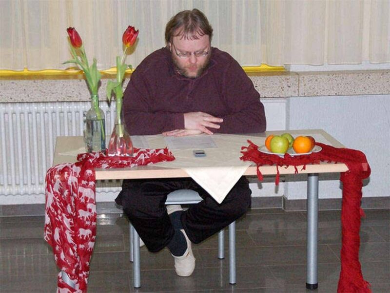 Foto: Ich sitze an einem mit Tüchern, Blumen undeibnem Obstteller geschmückten Tisch und lese meine Texte vor.