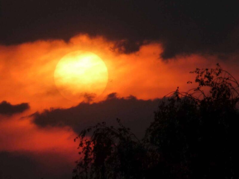 Der goldgelbe Sonnenball geht im Mainzer Westen in feuerroter Umgebung hinter dunklen Wolken unter.