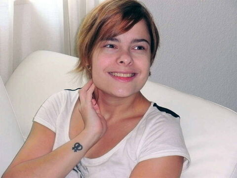 Foto: Akina sitzt ganz entspannt auf ihrem weißen Sofa und schaut lächelnd links an der Kamera vorbei.