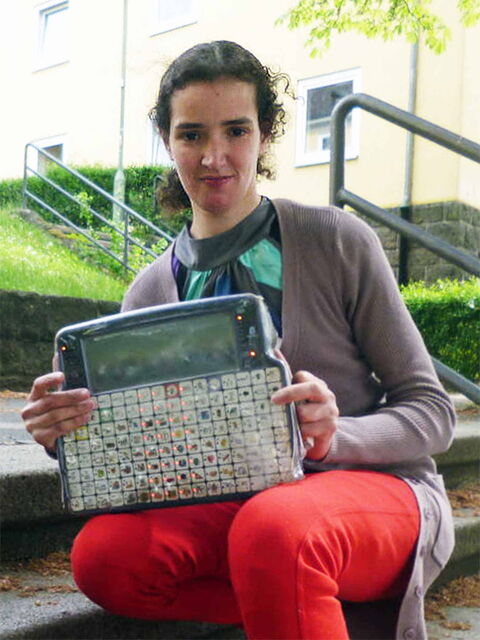 Foto: Fikria in roter Hose und fliederfarbener Strickjacke mit ihrem besten Freund, dem Talker.