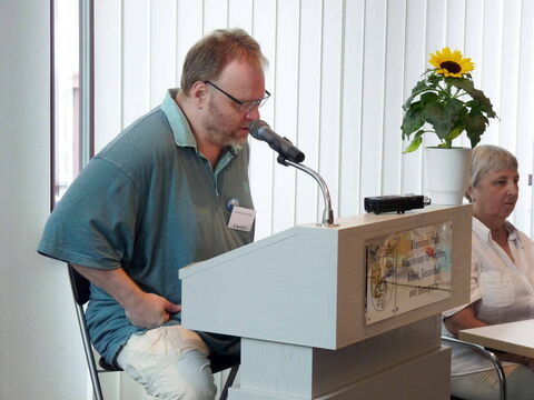 Foto: Hier sitze ich am Lesepult und lese meine Texte vor. Die Aufnahme ist im Halbprofil gemacht.