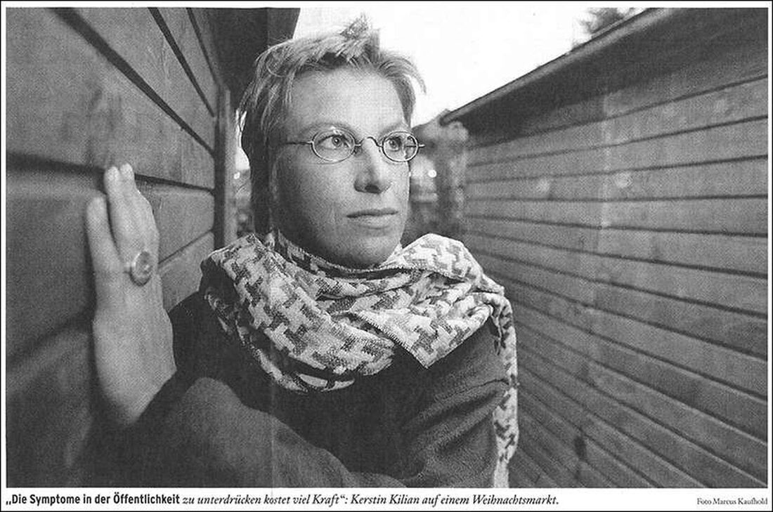 Foto: Ein schwarz/weiß-Foto von meiner Tourette-Bekannten Kerstin Kilian zwischen zwei Holzbuden eines Weihnachtsmarktes.