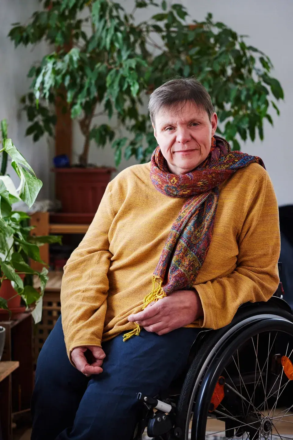 Foto: Andrea zuhause in ihrem Aktiv-Rolli vor etlichen grünen Pflanzen.