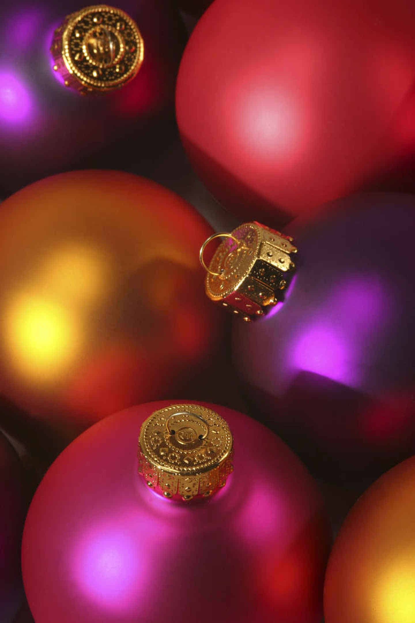 Foto: Verschiedenfarbige Christbaumkugeln in gelb, rot und violett.