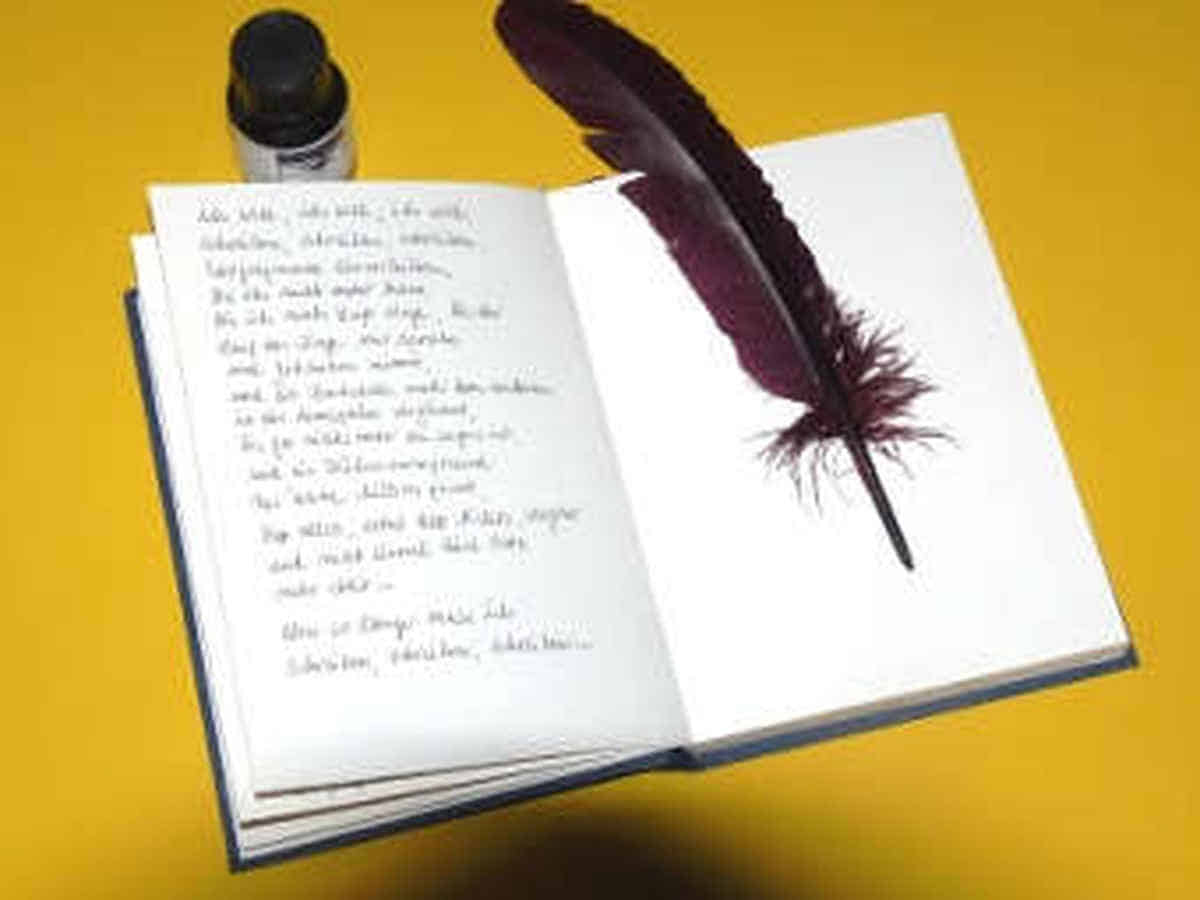 Foto: Das Buch liegt aufgeklappt auf dem Tisch. Links ist der Schluss  des Textes zu sehen, auf der rechten Seite liegt die Schreibfeder und  oberhalb des Buches steht das Tintenfass.