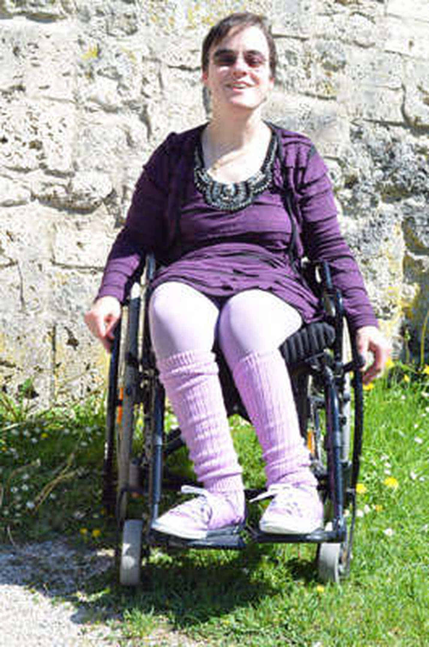 Foto: Die Uschimaus im lila Outfit in ihrem Rollstuhl.